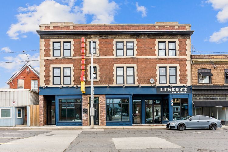 The Hendry's building on Barton St. E., seen on a sunny day, with refurbished neon sign and Hendry's Barbershop on the right.