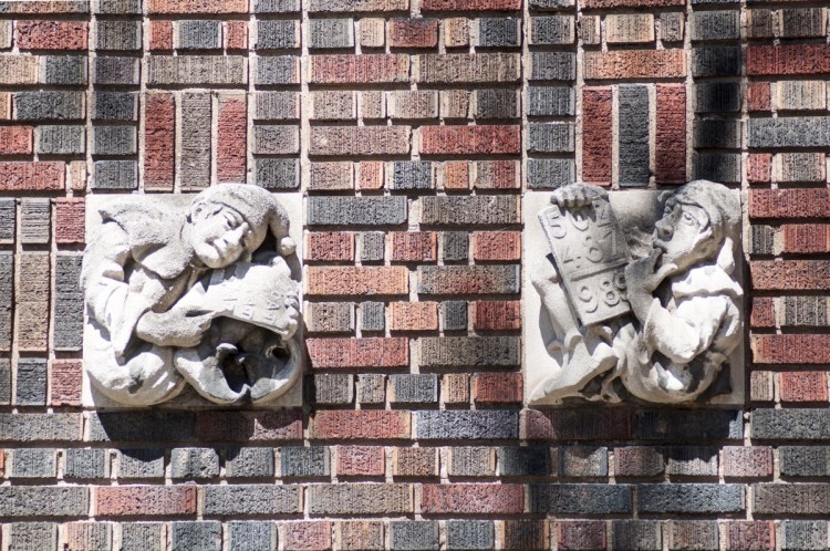 Neo-medieval carved decoration representing school work, against a ground of polychrome brick at the former McIlwraith School in Hamilton, Ontario. The decorations show two figures with tablets depicting reading and math.